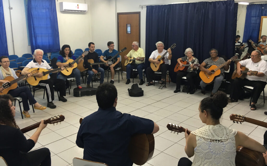 Carlos con grupo de personas tocando instrumentos en una sala